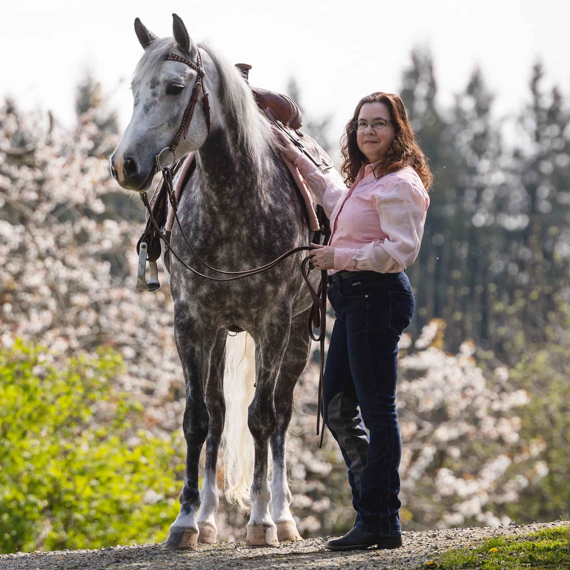 Jennifer Rader with her horse Ghost Whisperer on a backdrop of spring flowers